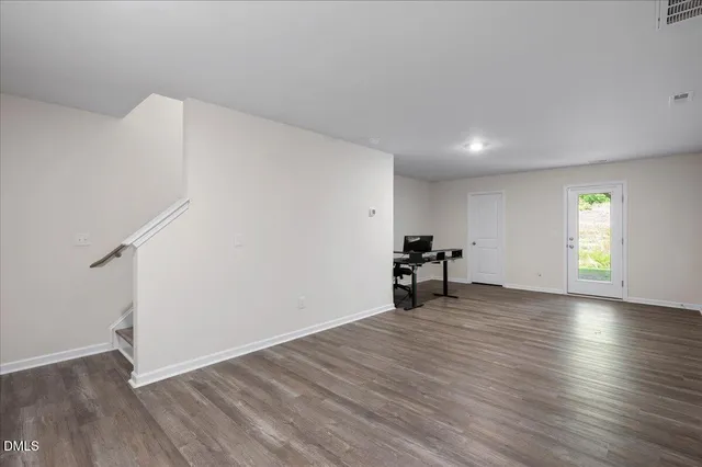 a view of empty room with wooden floor and window