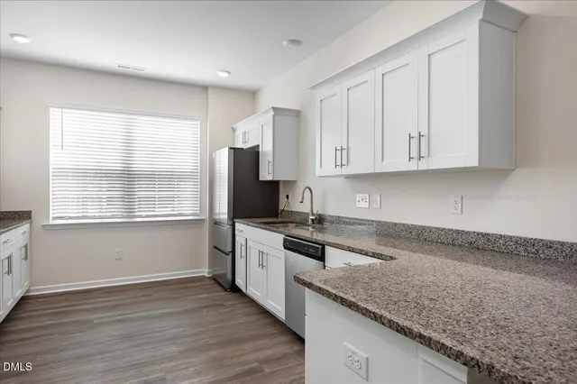 a kitchen with granite countertop wooden cabinets a sink and dishwasher