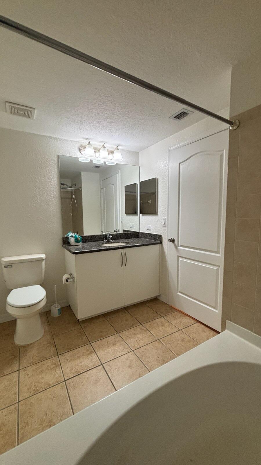 138 Southwest Peacock Boulevard, Unit 20105 Port St. Lucie, FL 34986 - Photo 10 of 19 a bathroom with a sink a toilet and mirror