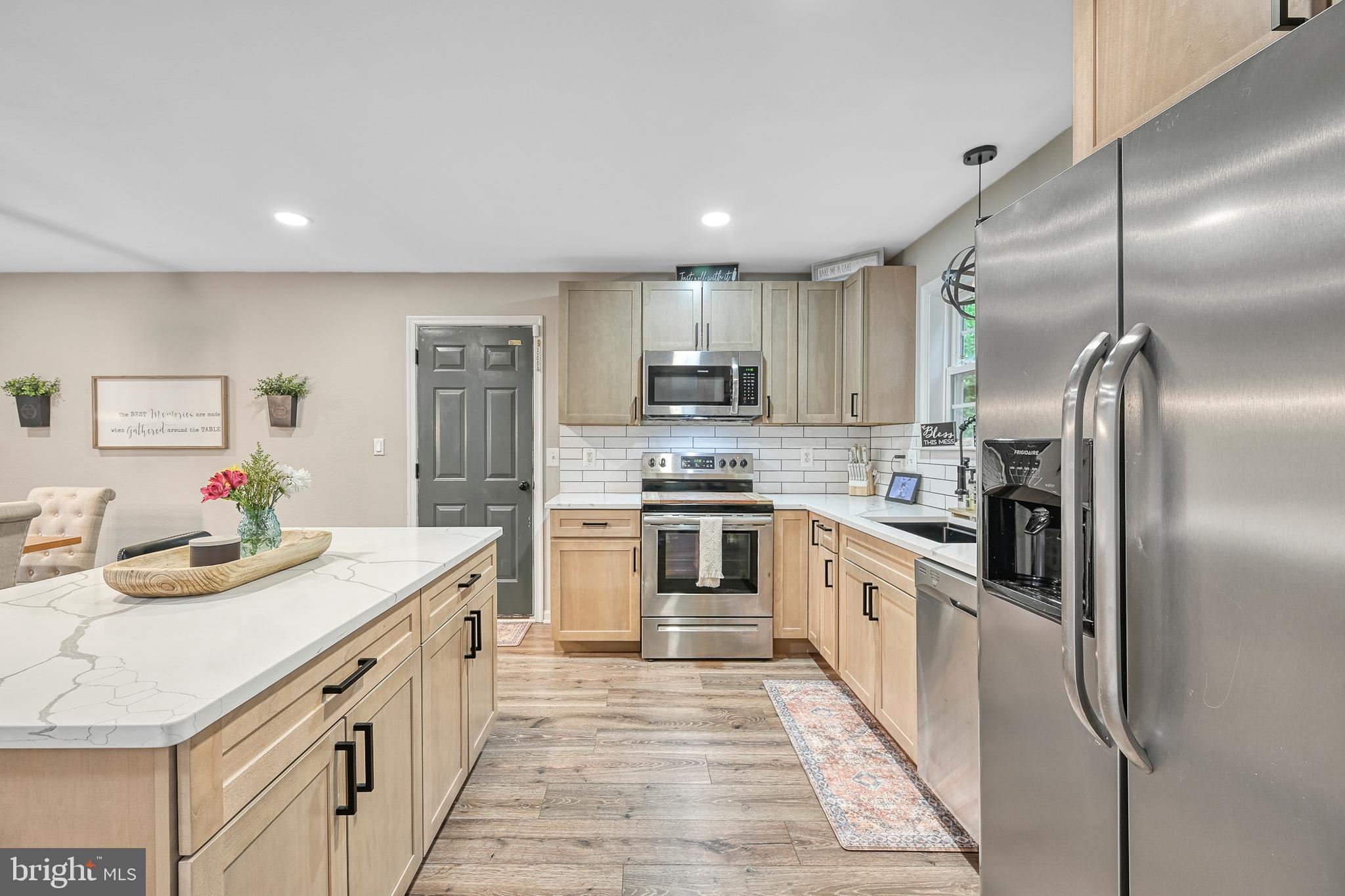 3605 Burton Road Bumpass, VA 23024 - Photo 8 of 39 a kitchen with stainless steel appliances kitchen island granite countertop a refrigerator a stove and a sink with wooden floor
