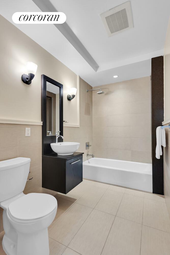 30-11 21st Street, Unit 5C Queens, NY 11102 - Photo 7 of 12 a bathroom with a bathtub sink mirror and toilet