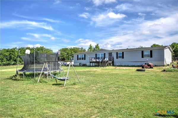 a view of house with a big yard and potted plants