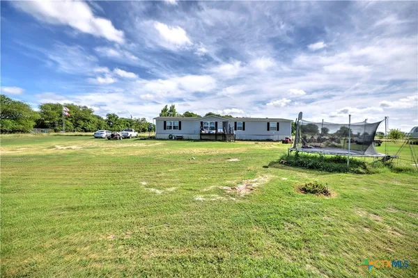 a view of a large pool with lawn chairs and a big yard