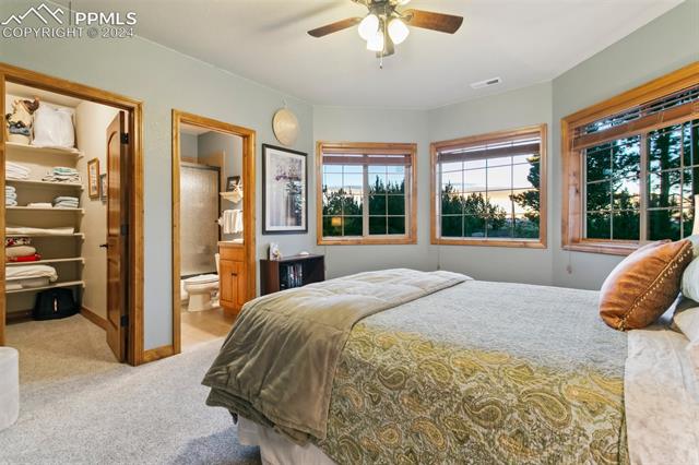 5470 Roundup Ridge Road Colorado Springs, CO 80908 - Photo 13 of 21 Carpeted bedroom with ensuite bathroom and ceiling fan