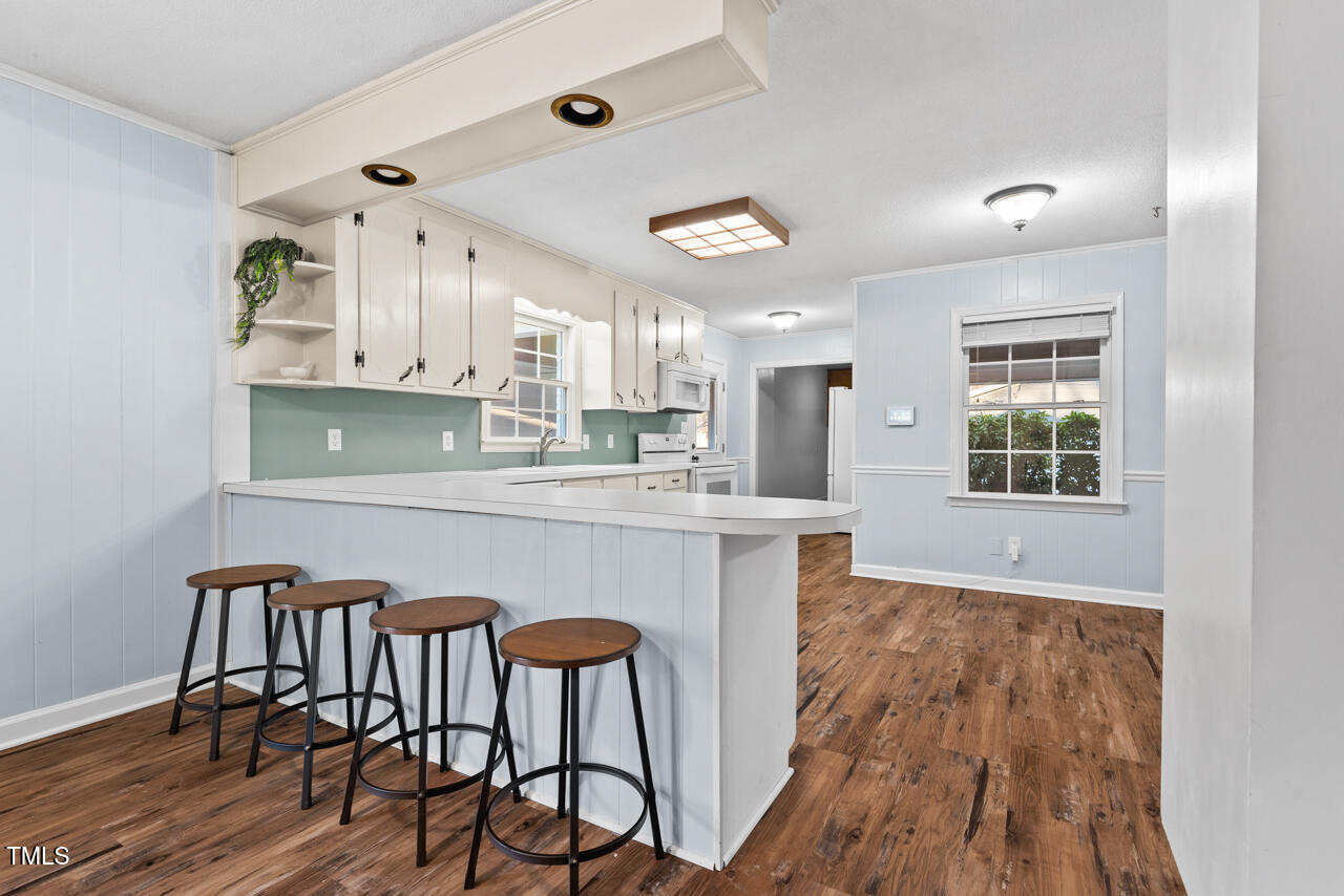 4908 Winterlochen Road Raleigh, NC 27603 - Photo 8 of 41 a kitchen with stainless steel appliances granite countertop a stove top oven a sink dishwasher and white cabinets with wooden floor