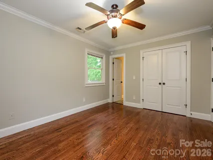 an empty room with wooden floor chandelier fan and windows