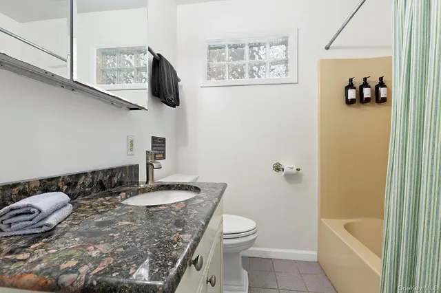 a bathroom with a granite countertop sink a toilet and bathtub