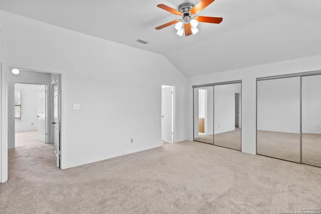 an empty room with closet and a chandelier fan