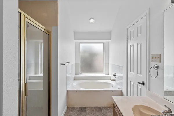 a bathroom with a granite countertop tub shower and a sink
