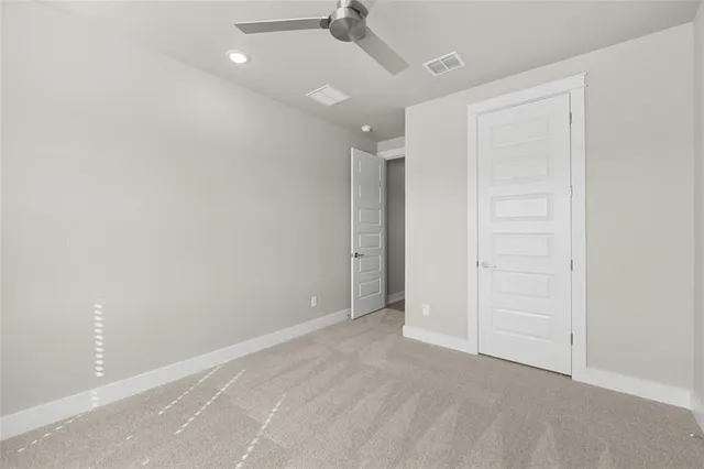 an empty room with closet and a chandelier fan