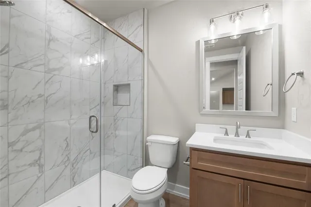 a bathroom with a toilet a sink a mirror and shower