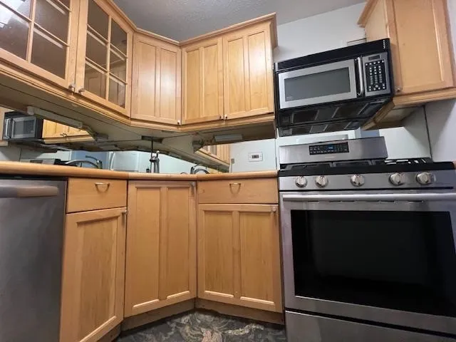 a kitchen with stainless steel appliances granite countertop a stove microwave and cabinets