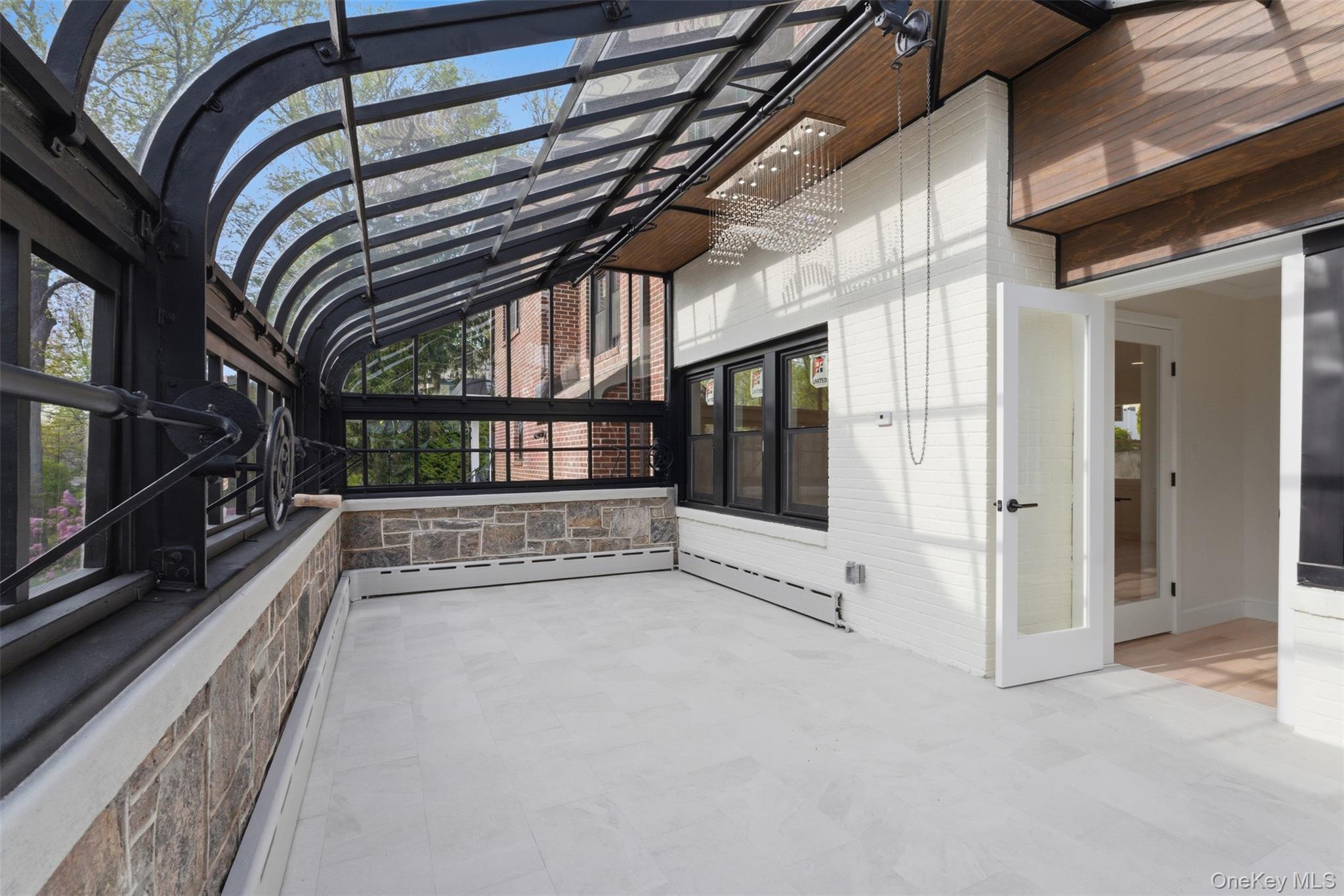 40 Calhoun Avenue New Rochelle, NY 10801 - Photo 15 of 49 Sunroom featuring a curved glass ceiling, stone half-walls, and white brick accents