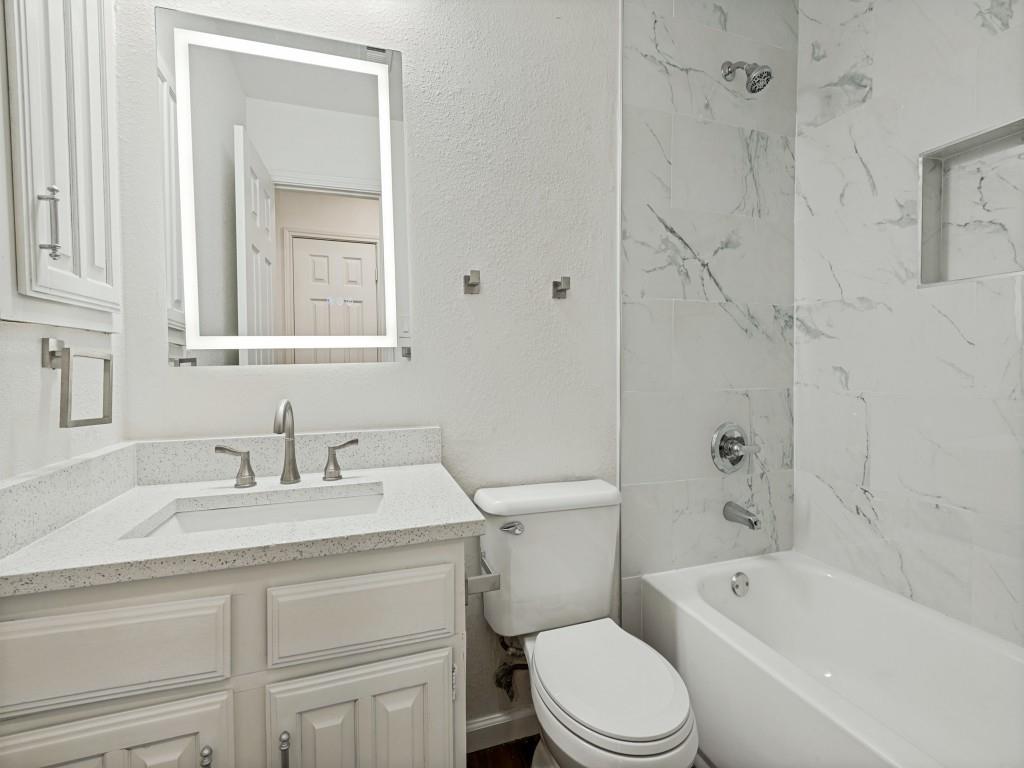 3716 Royal Valley Road Grand Prairie, TX 75052 - Photo 19 of 25 Spa-inspired bathroom featuring a marble-look tile shower enclosure with integrated shelving, white subway tile accents, and polished chrome fixtures