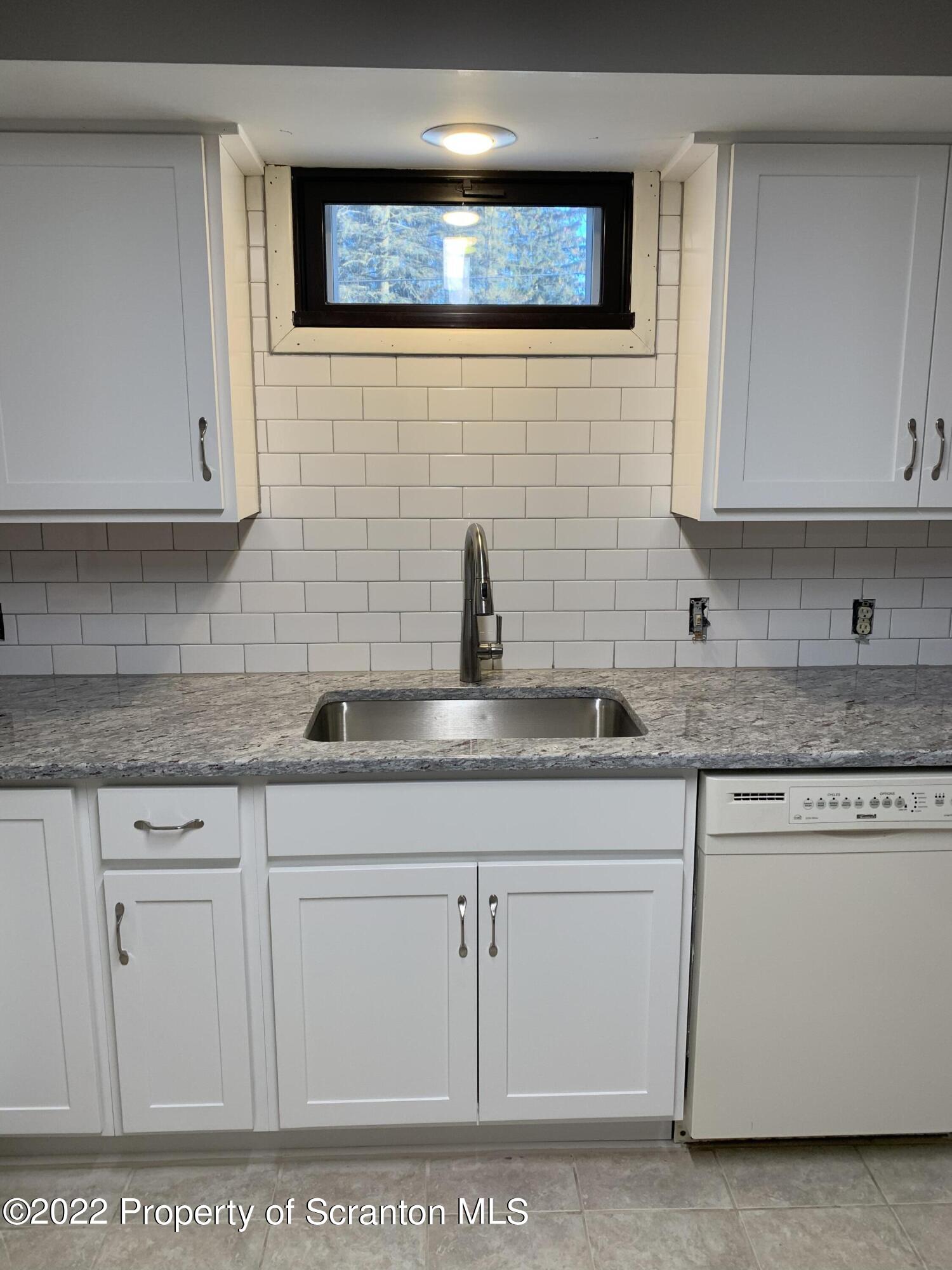 a kitchen with white cabinets a sink and dishwasher