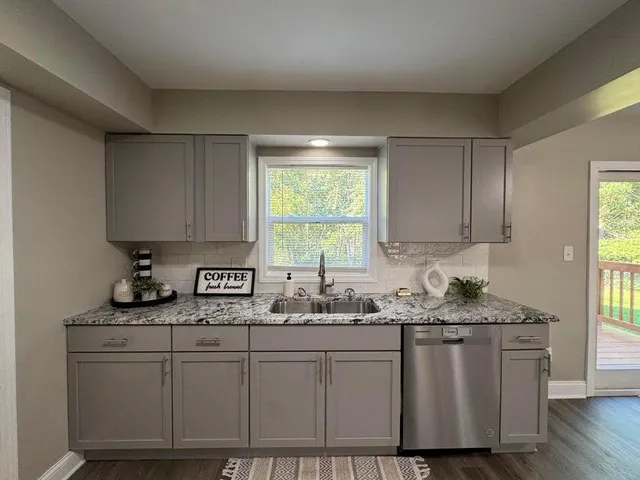 a kitchen with granite countertop white cabinets white appliances and a window