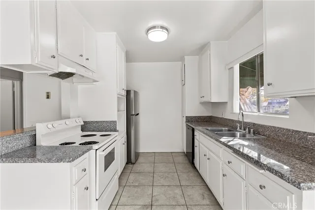 a kitchen with granite countertop a sink stove and refrigerator