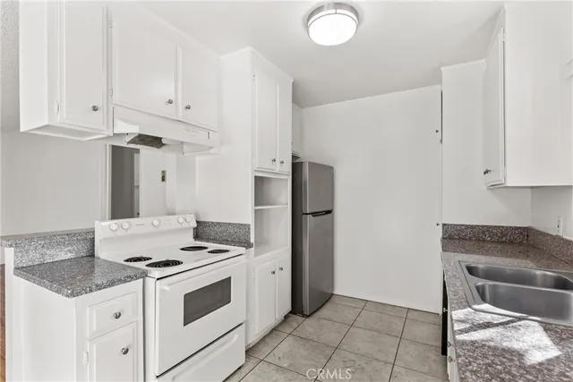 a kitchen with granite countertop a sink stove and refrigerator