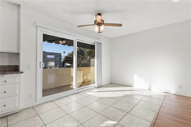 a view of an empty room with window and chandelier fan