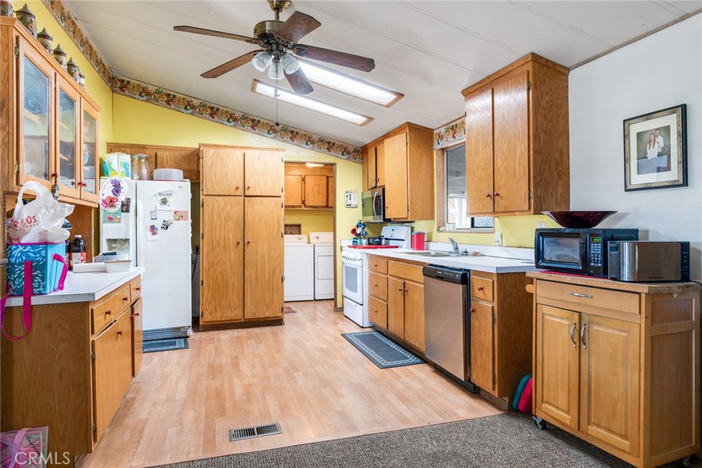 14250 Howe Place Beaumont, CA 92223 - Photo 19 of 31 a open kitchen with stainless steel appliances kitchen island granite countertop a refrigerator a stove a sink dishwasher and white cabinets with wooden floor