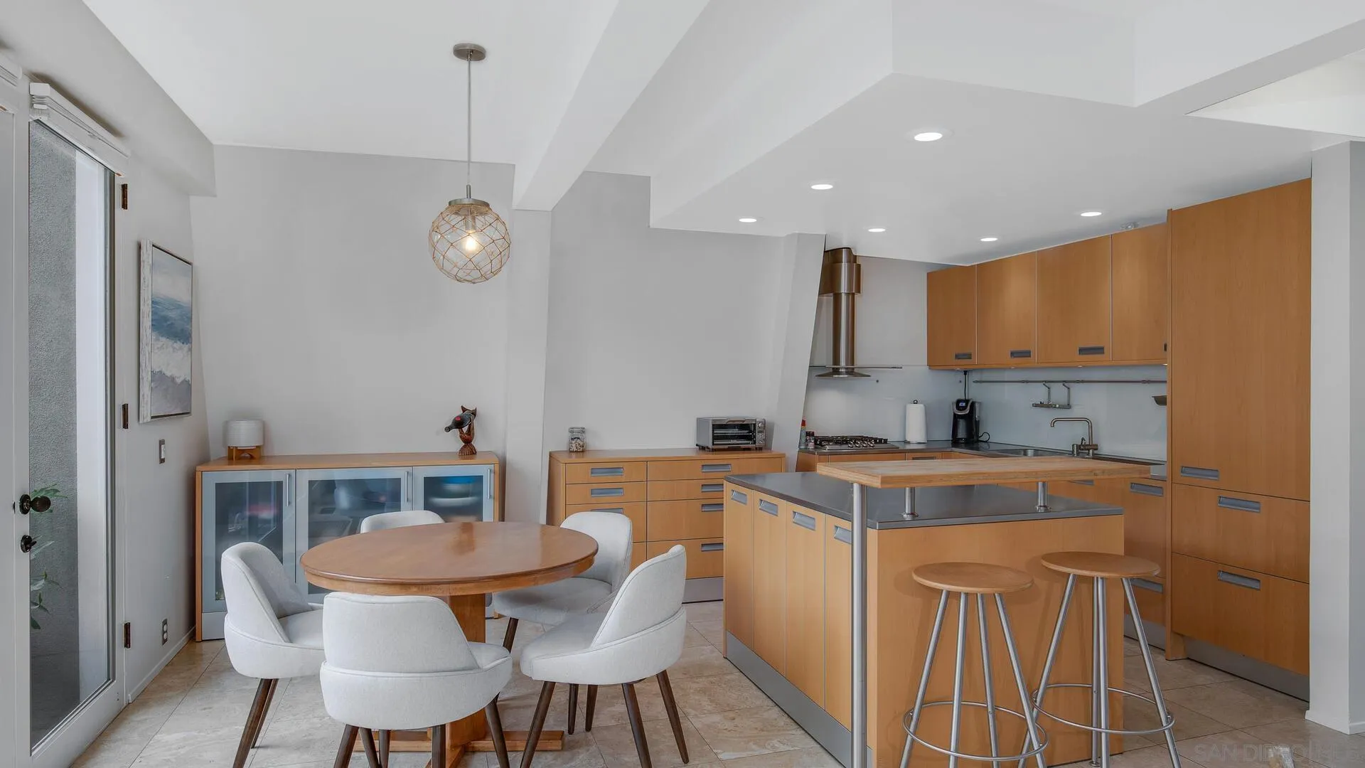 549 Rimini Road Del Mar, CA 92014 - Photo 3 of 32 a kitchen with a table chairs a sink dishwasher and cabinets