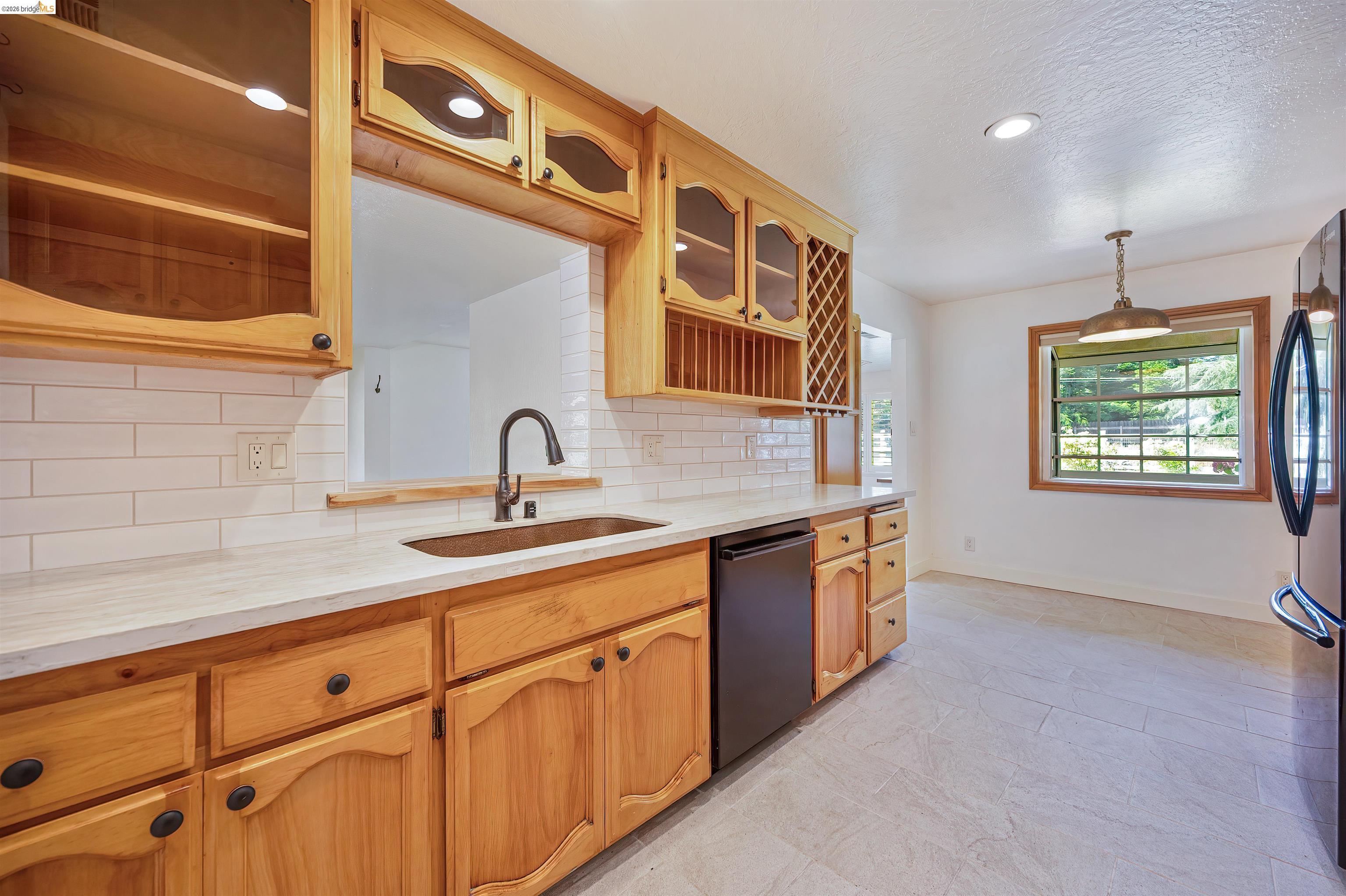 10474 Sheldon Road Elk Grove, CA 95624 - Photo 23 of 83 Light wood cabinetry with black hardware, white subway tile backsplash, and light-toned countertops