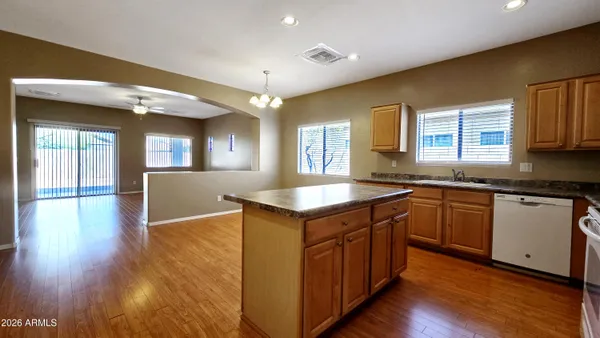 a kitchen with a stove kitchen island and a sink cabinets with wooden floor