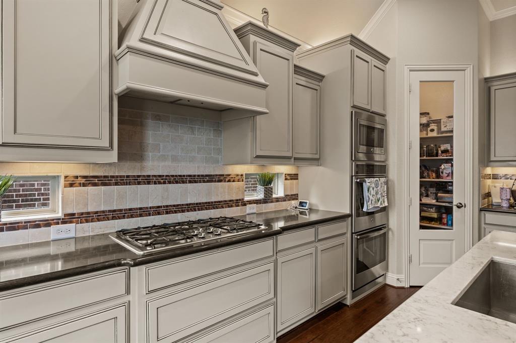 616 Whitetail Road Euless, TX 76039 - Photo 12 of 39 Kitchen with gray cabinets, tasteful backsplash, custom exhaust hood, dark wood-type flooring, and crown molding