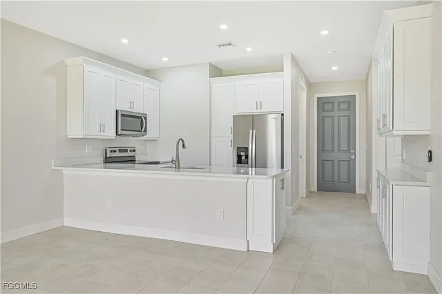 a large white kitchen with stainless steel appliances granite countertop a refrigerator and a stove top oven