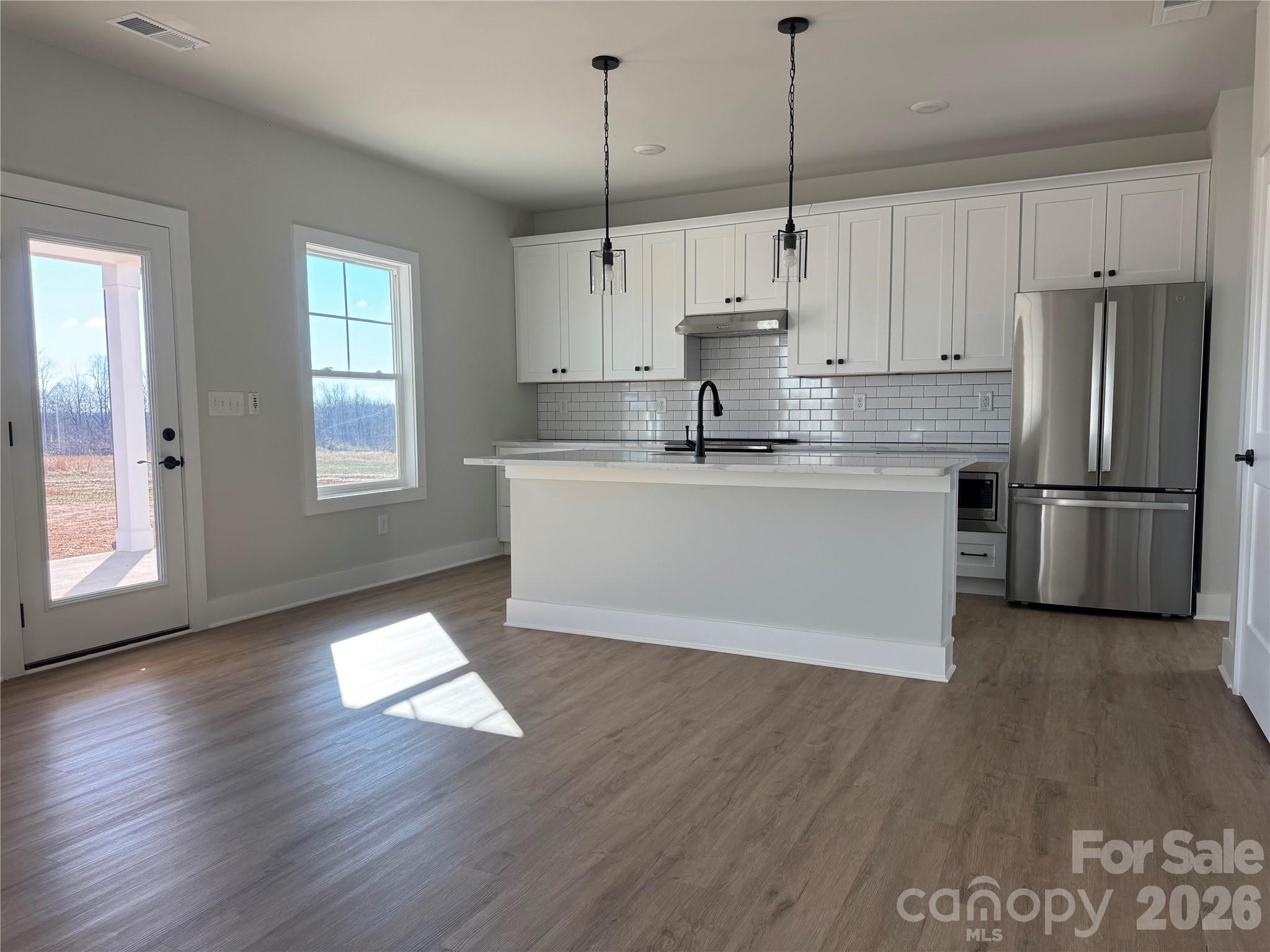 2440 Sandy Springs Road Mocksville, NC 27028 - Photo 3 of 15 a kitchen with stainless steel appliances granite countertop a refrigerator a sink dishwasher a stove and white countertops with wooden floor
