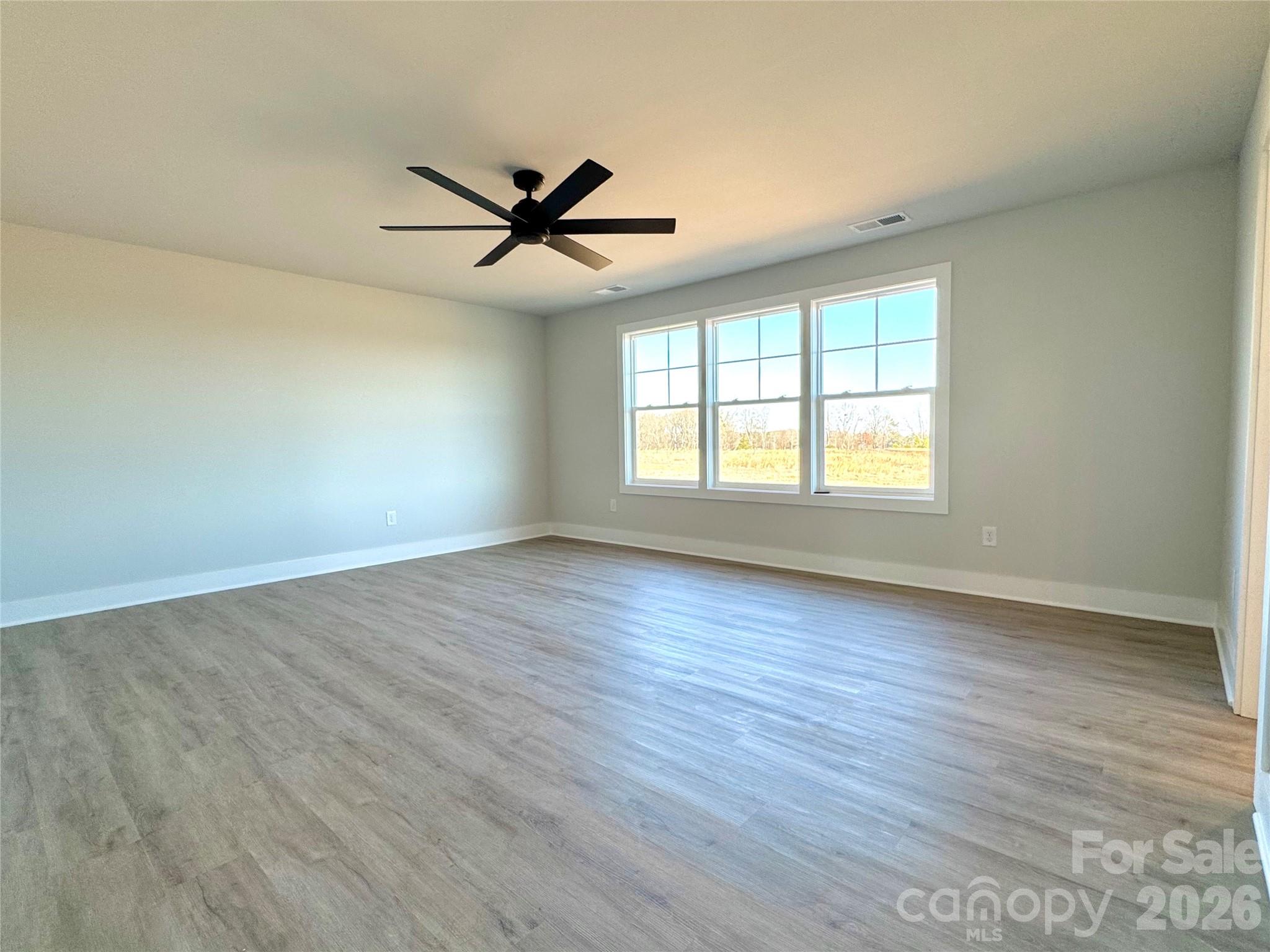 2440 Sandy Springs Road Mocksville, NC 27028 - Photo 8 of 15 an empty room with wooden floor fan and windows