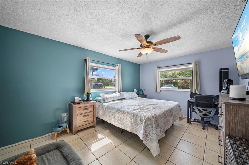 7289 Barragan Road Fort Myers, FL 33967 - Photo 13 of 18 Bedroom featuring light-toned tile flooring, dual windows with natural light, and a ceiling fan with integrated lighting