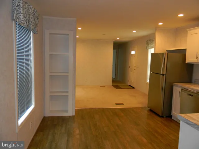 an empty room with wooden floor and a refrigerator