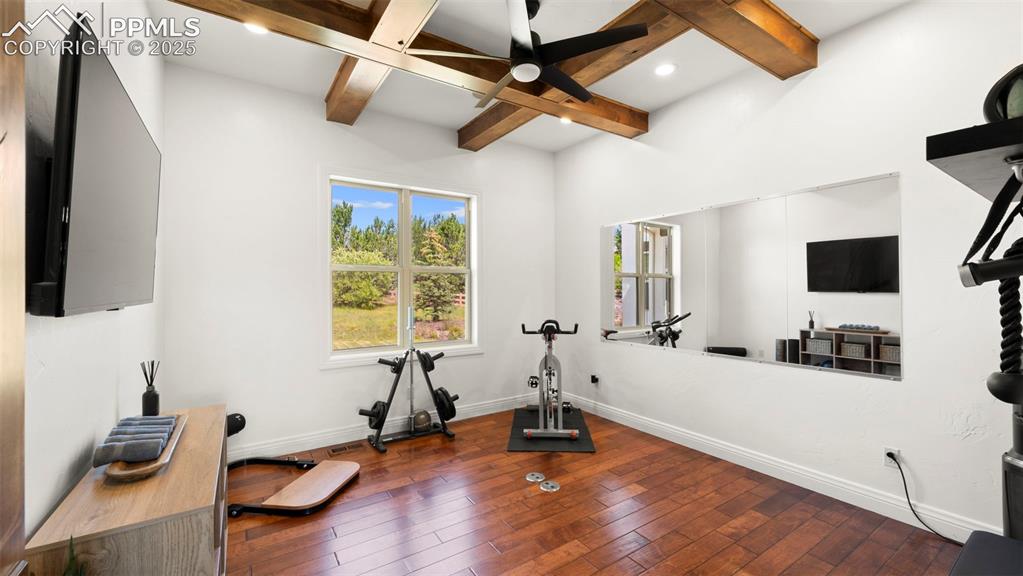 13625 Random Ridge View Colorado Springs, CO 80921 - Photo 8 of 50 Exercise area with dark wood finished floors, a ceiling fan, and coffered ceiling