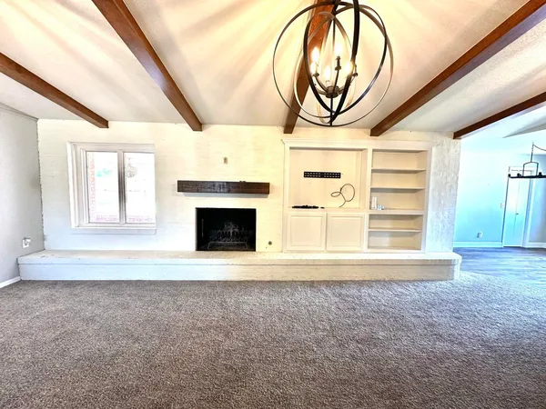 a view of an empty room with a fireplace and a window
