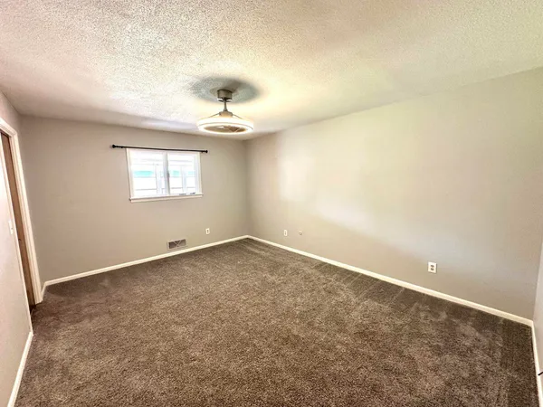 an empty room with windows and chandelier fan