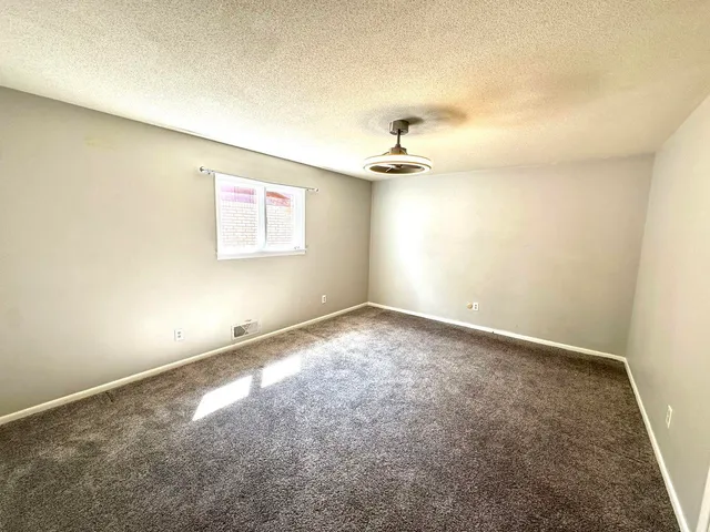 an empty room with a ceiling fan and window