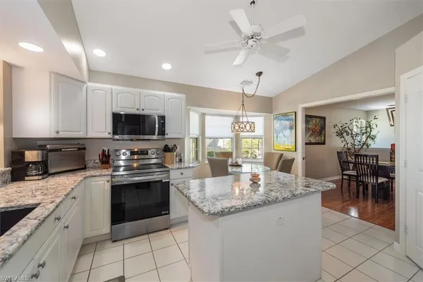 a kitchen with stainless steel appliances granite countertop a stove top oven a sink dishwasher a dining table and chairs with wooden floor