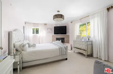 a bedroom with a bed and a flat tv screen on dresser