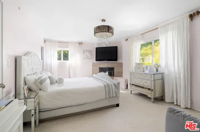a bedroom with a bed and a flat tv screen on dresser