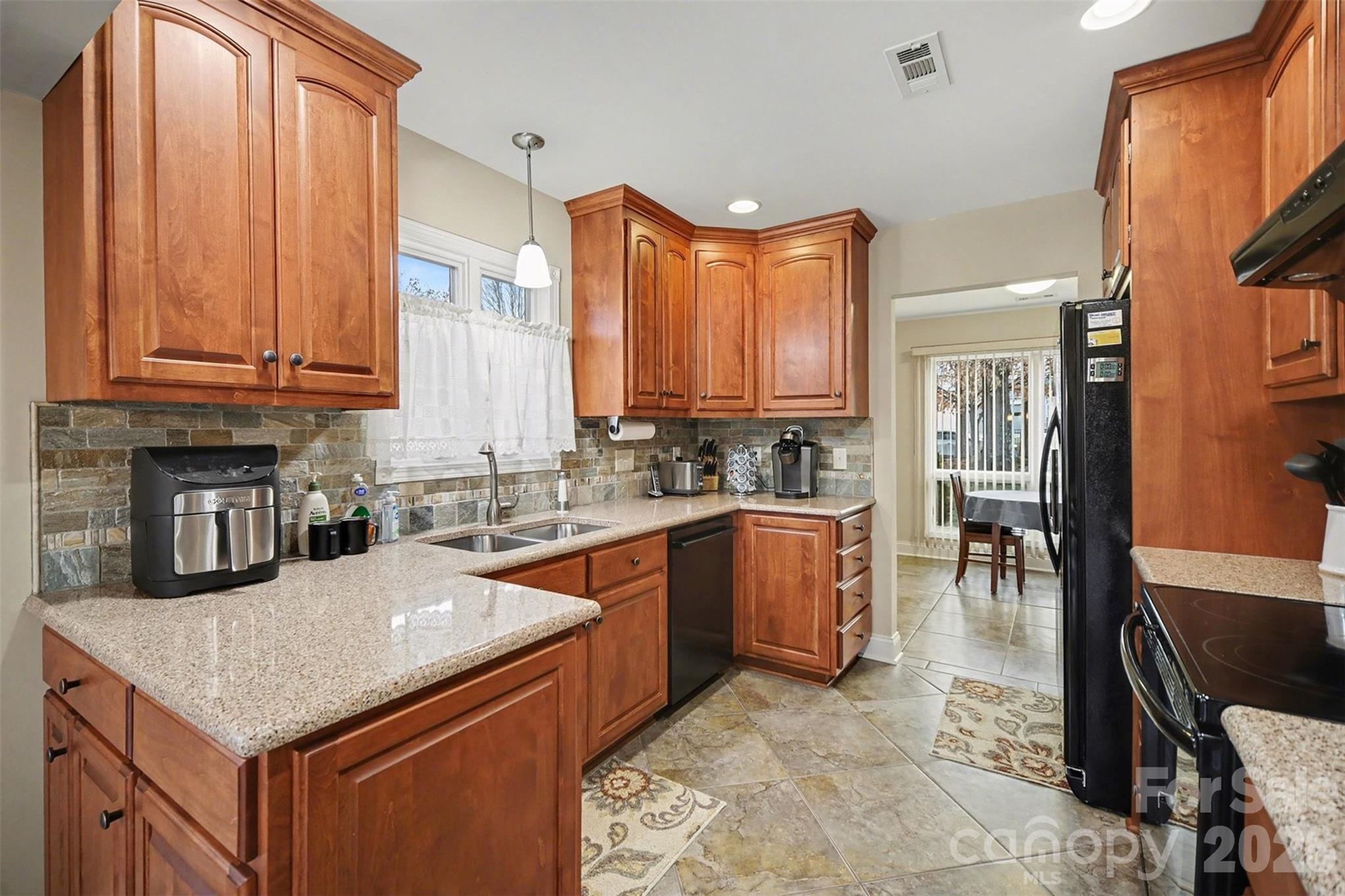9325 Chislehurst Road Mint Hill, NC 28227 - Photo 12 of 30 a kitchen with stainless steel appliances granite countertop a stove a sink dishwasher and a refrigerator with wooden cabinets