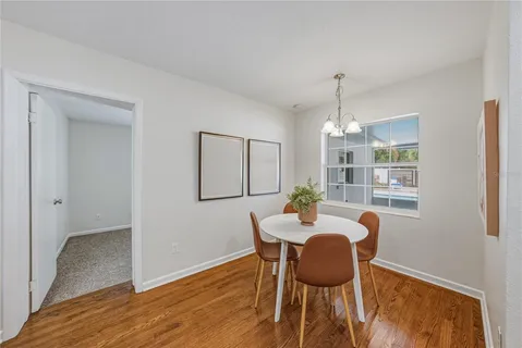 a kitchen with stainless steel appliances granite countertop a dining table chairs and refrigerator