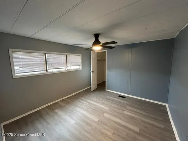 an empty room with wooden floor chandelier and windows