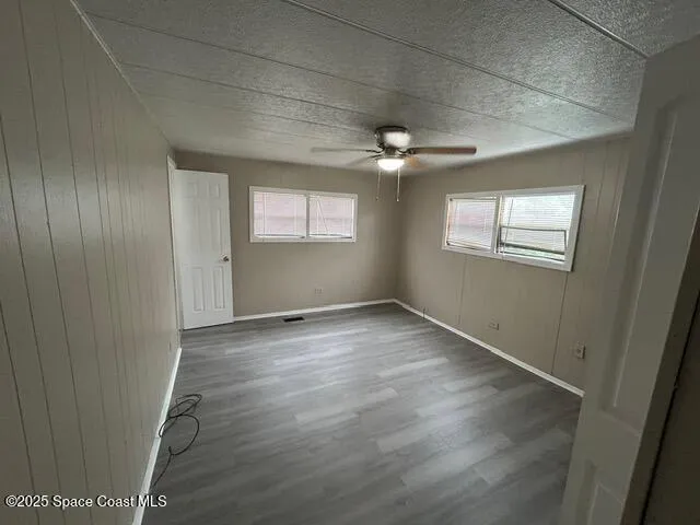 an empty room with wooden floor chandelier and windows