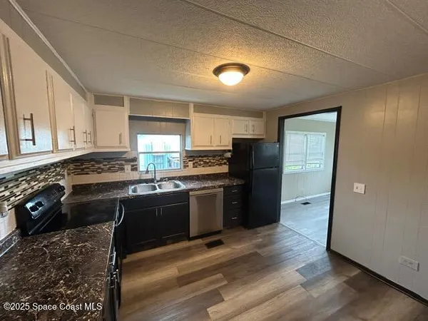 a kitchen with granite countertop a refrigerator stove and sink