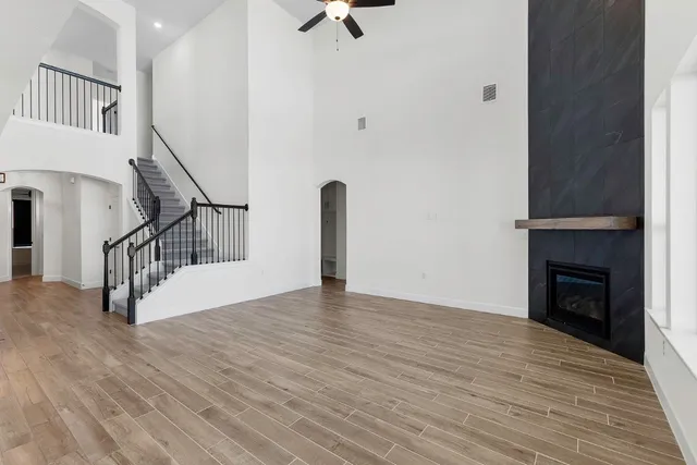 a view of an empty room with wooden floor and a fireplace