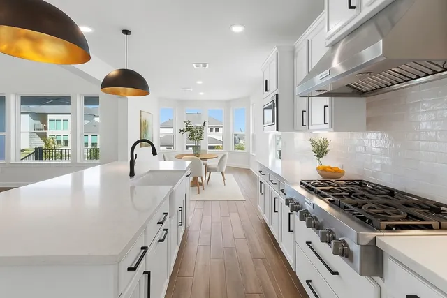 a kitchen with stainless steel appliances granite countertop a stove a sink a refrigerator and a dining table with wooden floor