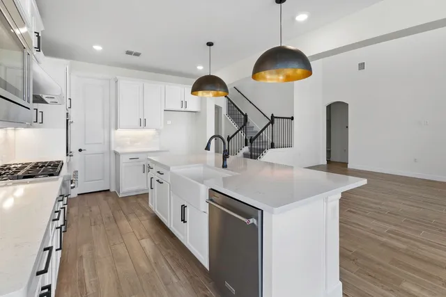 a kitchen with stainless steel appliances granite countertop a sink a stove and a wooden floors