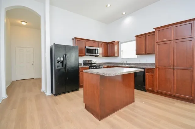 a kitchen with stainless steel appliances granite countertop a refrigerator a stove a sink and a microwave