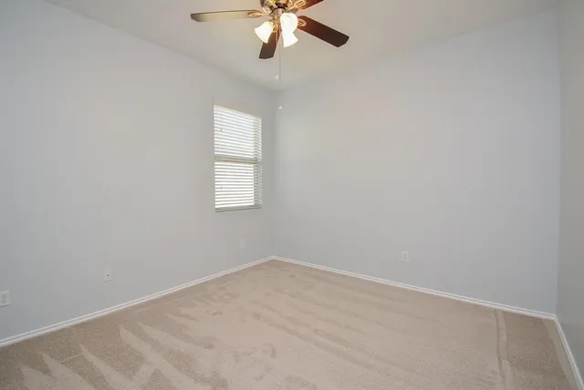 an empty room with a window and a fan